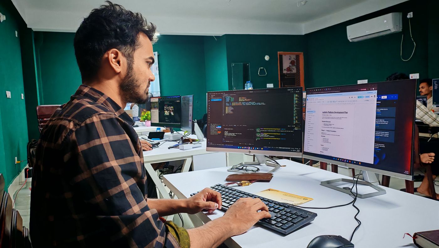 Someone working at a desk with two monitors