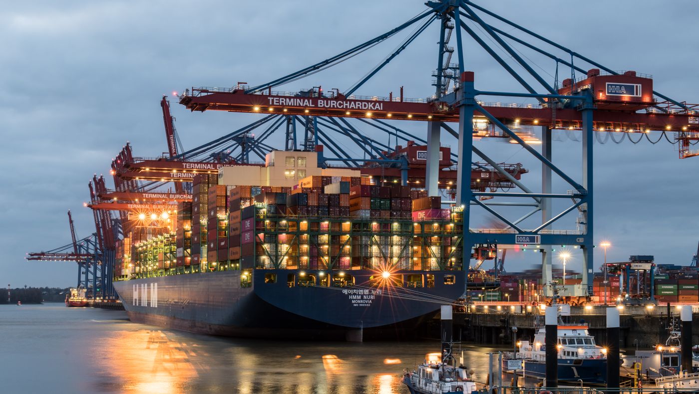 Cranes and stacked containers at a port terminal at dusk